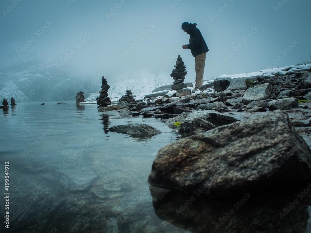 Obraz premium many balanced stone man tower reflecting in the water of a glacier lake in the alps