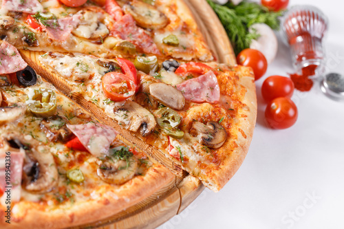 Italian kitchen and cooking concept. Hot tasty sliced with ham, sausage, jalapenos, mushrooms, tomato. Eat delivery concept.