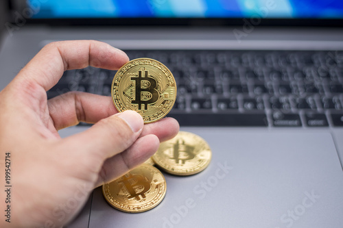 male hand holding bitcoin on a laptop background.