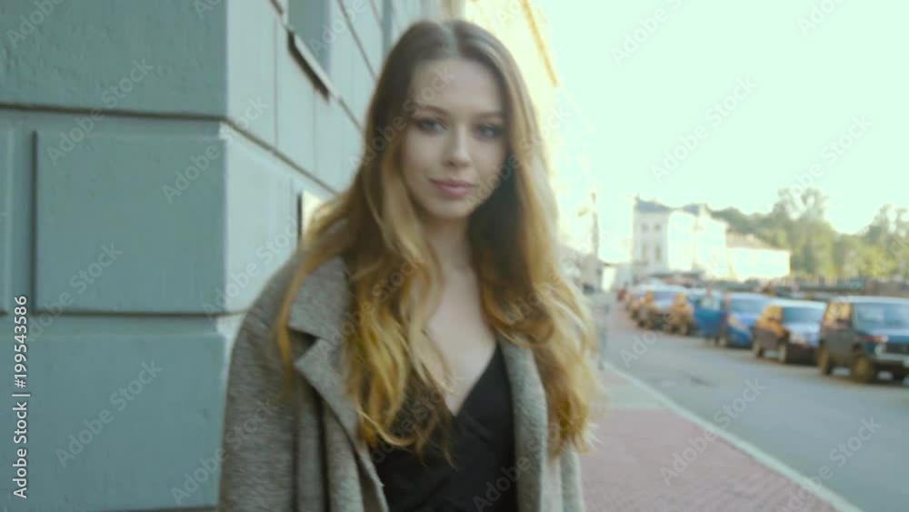 Cheerful girl with deep décolleté stands and walks in a city street in slo-mo Cheerful girl with deep décolleté stands and walks in a city street in slo-mo