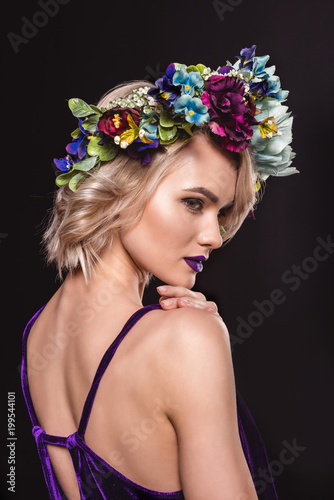 attractive blonde model posing in floral wreath, isolated on black