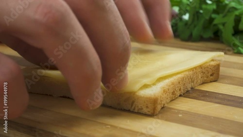 Making sandwich with white bread, ham, salad, tomatoes