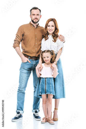 happy parents with adorable little daughter standing together and smiling at camera isolated on white