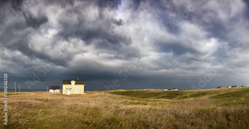 Panorama of an old fisherman's cottage on the clifftop with dramatic storm clouds. Havre Abert, Ilse de la Madeleine, otherwise known as the Magdalen Islands, Canada photo