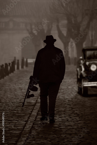 Silhouette of a gangster with machine gun, on a street with fog photo