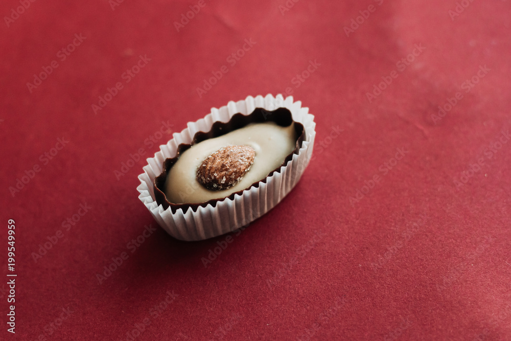 Flat lay of delicious praline sweets with almonds on red background Flat lay of delicious praline sweets with almonds on red background