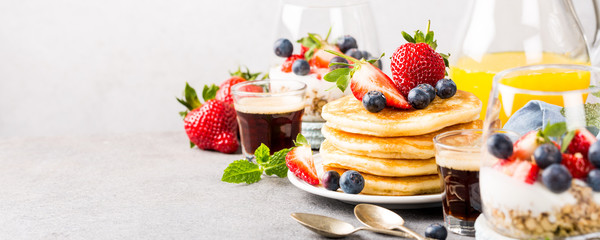 Breakfast composition with fresh pancakes and berries on light gray concrete background. Healthy food concept with copy space. Banner.