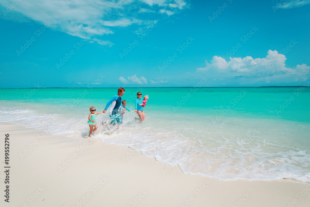 happy family with kids play with water run on beach