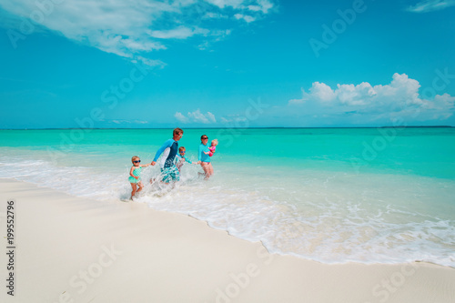 happy family with kids play with water run on beach