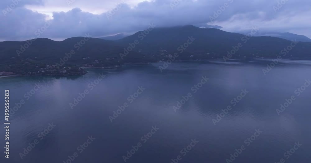 Aerial, island coast with beautiful calm sea in the evening and overcast sky Aerial, island coast with beautiful calm sea in the evening and overcast sky