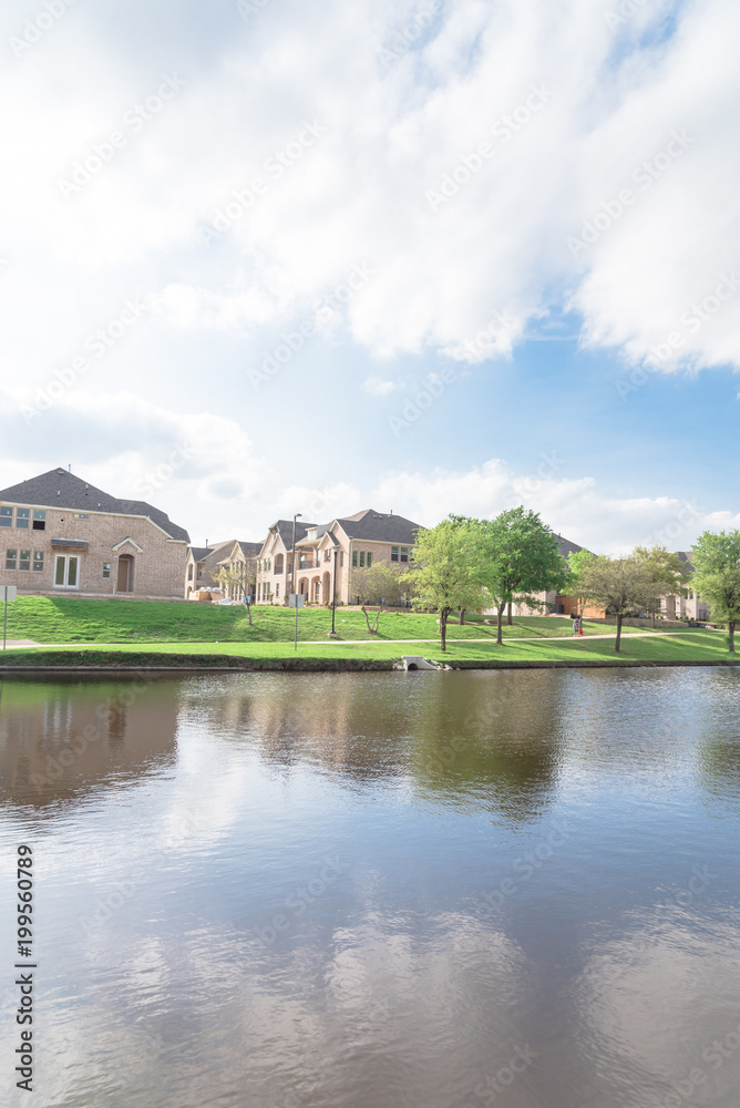 Typical lakeside new-established community with newly built detached single-family homes. Cloud blue sky reflection near urban park with walking path in suburban Irving, Texas, USA Typical lakeside new-established community with newly built detached single-family homes. Cloud blue sky reflection near urban park with walking path in suburban Irving, Texas, USA