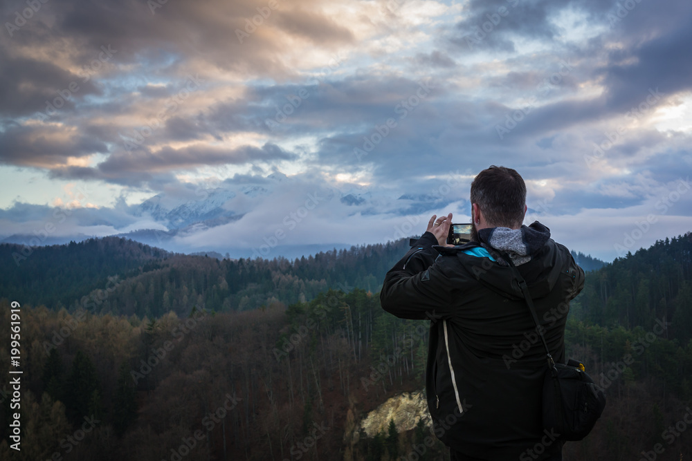 Mann fotografiert berg bei sonnenuntergang mit wolken
