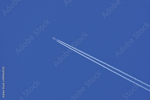 airplane with vapor trail in blue sky