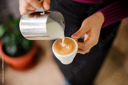 Barista adding a milk to the cup of espresso