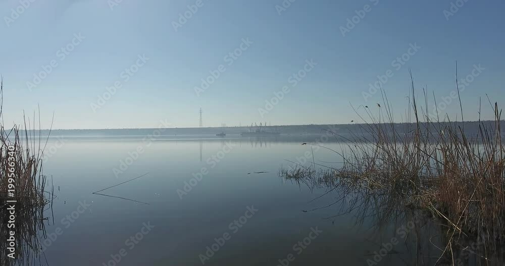 Top view from the shore of the morning river to the open water with working ships in the distance Top view from the shore of the morning river to the open water with working ships in the distance