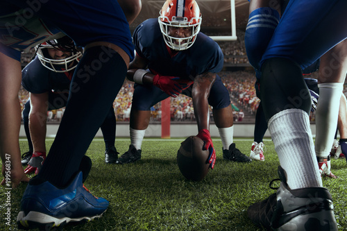 American football players preforms an action play in professional sport stadium