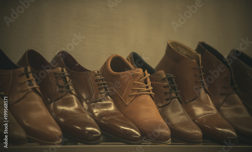 Row of leather mens shoes. Mens shoes, boot sell in store, boutique, shopping mall. Mens shoes concept. Mens fashion, style, quality, leather, leatherette. Shelf with brown mens shoes.