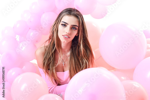 Close-up portrait of pretty young woman with long hair laying in pink balloons. Party mood. Gorgeous woman with colorful balloons. Celebration concept. © Svitlana