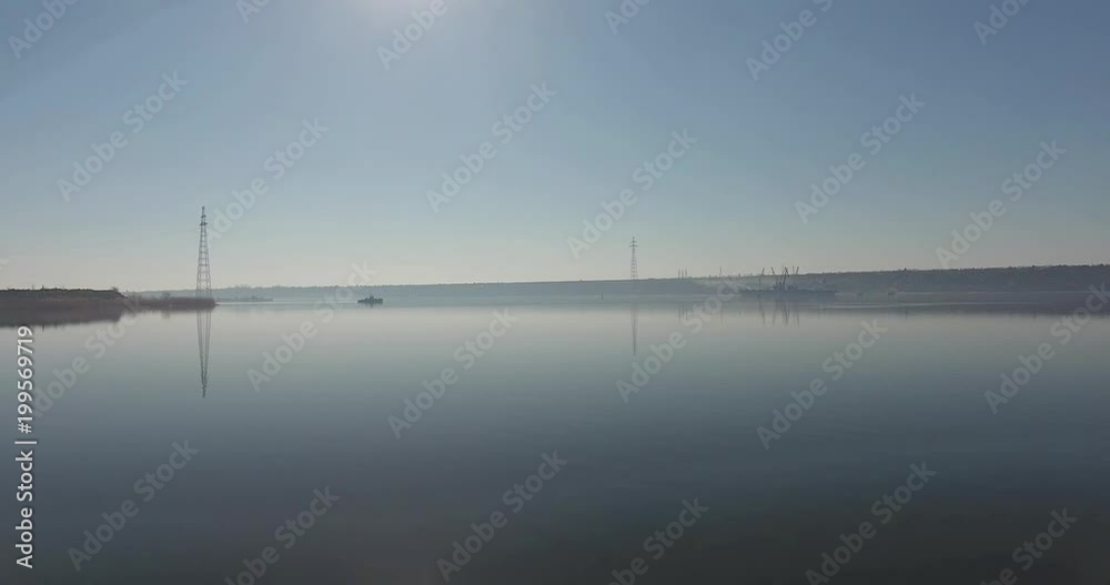 Aerials view from above on expanse of morning river with electric masts and working ships onhorizon Aerials view from above on expanse of morning river with electric masts and working ships onhorizon