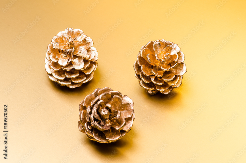 three golden pine cone on a golden background three golden pine cone on a golden background
