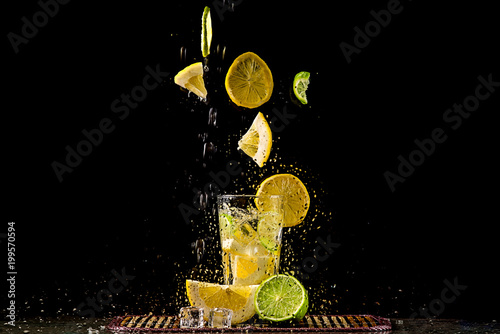 Levitating slices of lemon and lime, a splash of water.