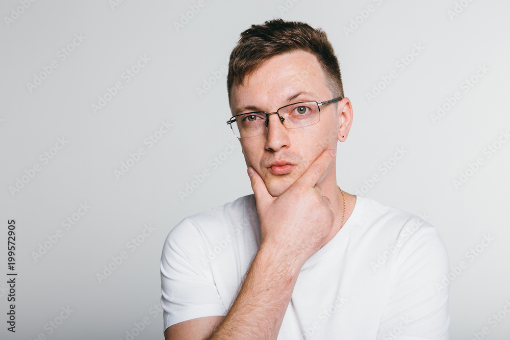 Man thinking and concentrated  while standing against grey background.