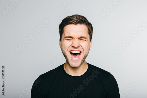 Anger, rage, shout man standing on grey background.