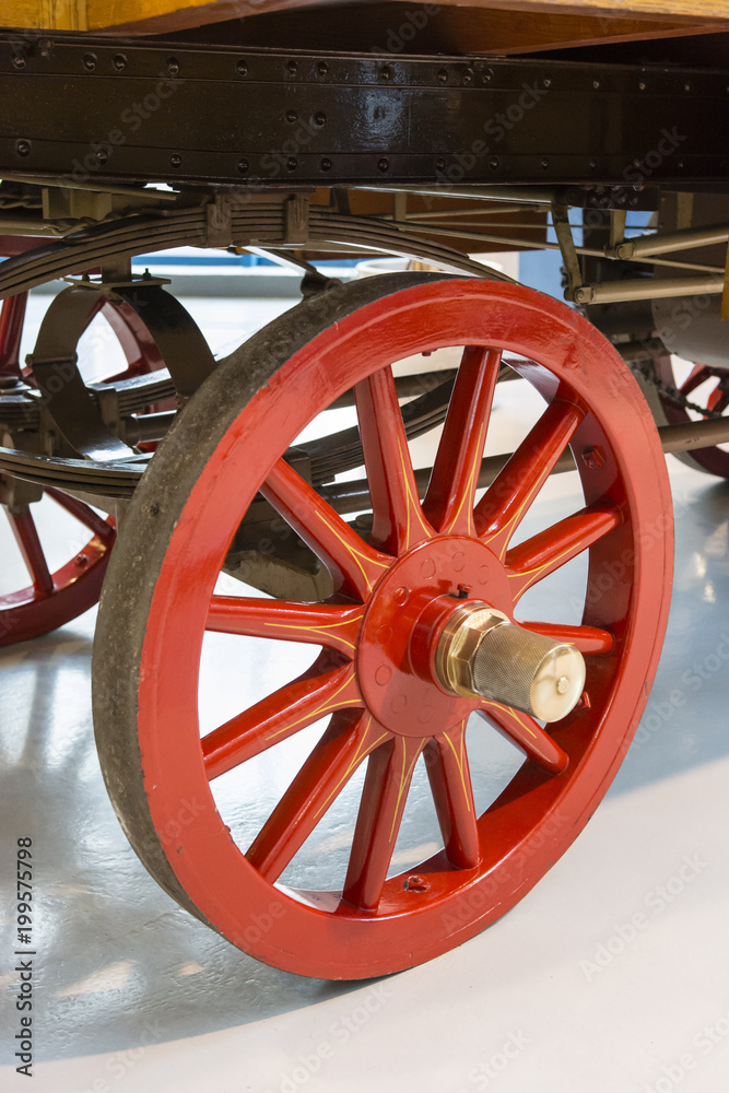 An old red-rimmed round wheel with leaf fingers.