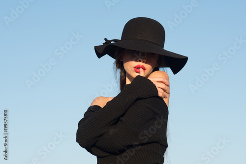 portrait of a young beautiful fashionable woman wearing stylish accessories. Hidden eyes with hat. Female fashion, beauty and advertisement concept. Close up.