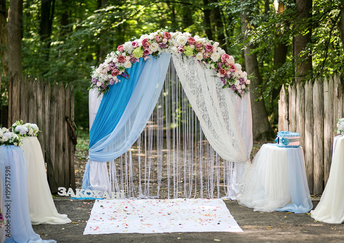 arch decorated with pink and white flowers standing in the woods