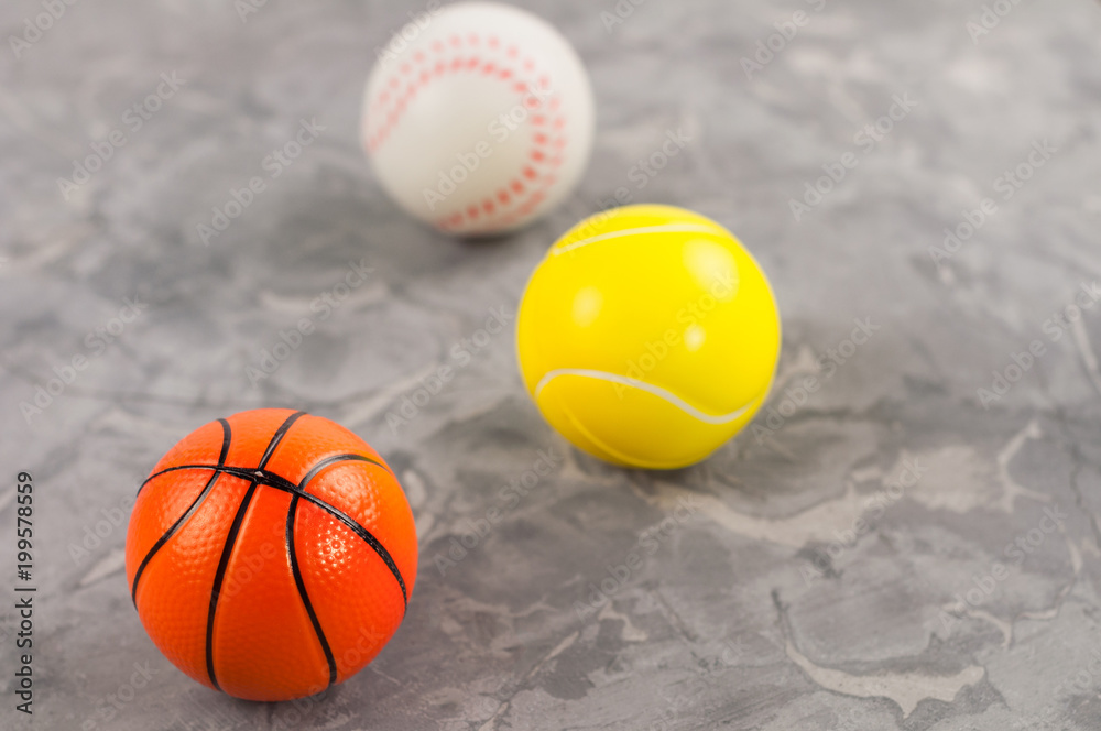 Three new soft rubber baseball and basketball and tennis balls on old worn cement