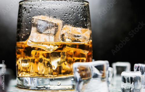 whiskey in a glass of ice on a black background. Alcoholic beverages
