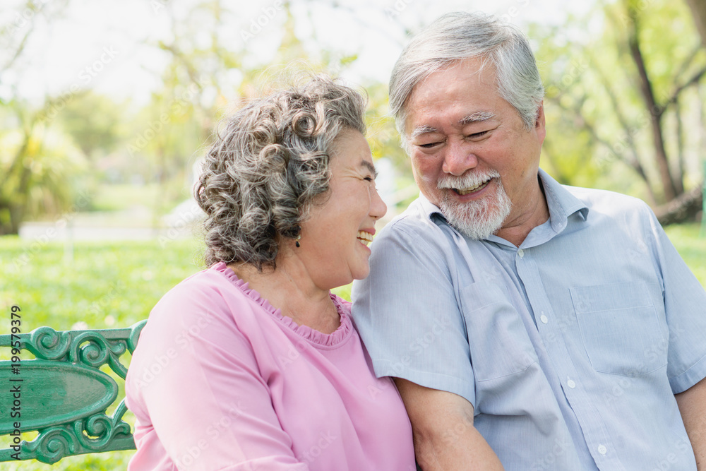 Asian healthy senior couple relaxing seated in the park together. Asian healthy senior couple relaxing seated in the park together.