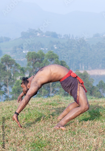 Indian man doing yoga exercises on green grass in Kerala, South India