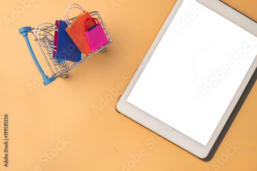 Minimal shoping online concept, Colorful paper shopping bag and trolley go down from floating yellow background for copy space. Customer can buy everthing form home and the messenger will deliver. photo