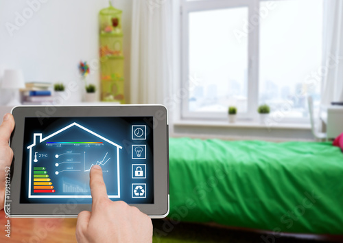 smart home and technology concept - close up of male hands pointing finger to tablet pc computer with house settings on screen over kids room background