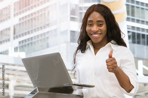 Photography Young african lady showing thumbs up and smile with laptop computer