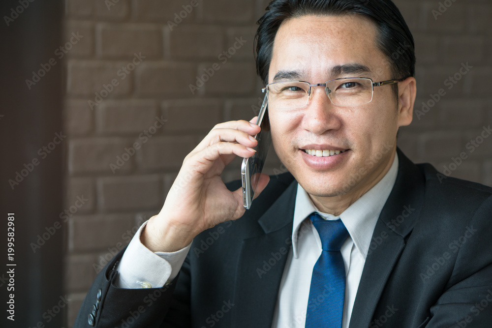 Successful asian CEO talking mobile phone. Successful asian CEO talking mobile phone.