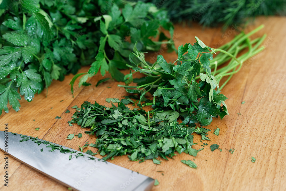 Freshly chopped up bunch of parsley on wood chopping board next to kitchen knife. Freshly chopped up bunch of parsley on wood chopping board next to kitchen knife.