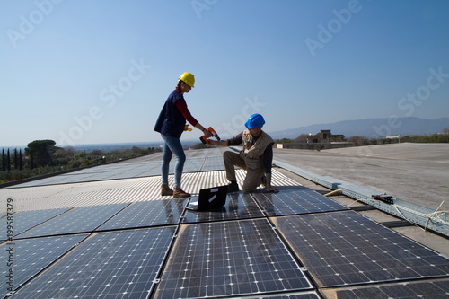 young engineer girl and an elderly skilled worker fitting a photovoltaic plant