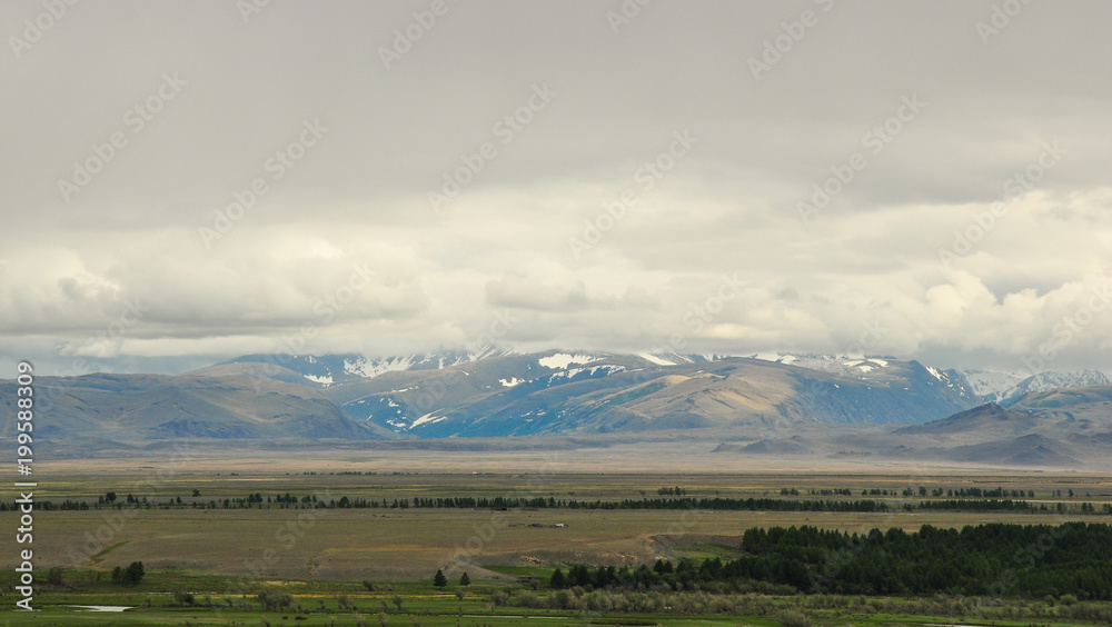 Aerial Altai mountains landscape. Mountain range behind wooded plains