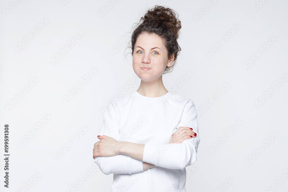 Close up ofCaucasian fermale with funky hair blows cheeks, looks surprised, makes fool or grimace, being amazed by excited news. Young pretty lady student expresses great joy because of good mark. Close up ofCaucasian fermale with funky hair blows cheeks, looks surprised, makes fool or grimace, being amazed by excited news. Young pretty lady student expresses great joy because of good mark.