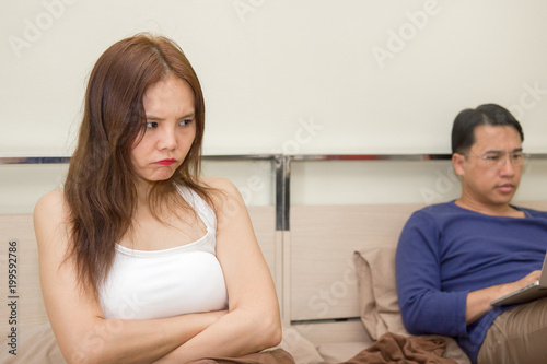 Concept problems in family relationship. Husband overworking with computer on the bed in the house and ignore his wife. Wife petulant her man. photo