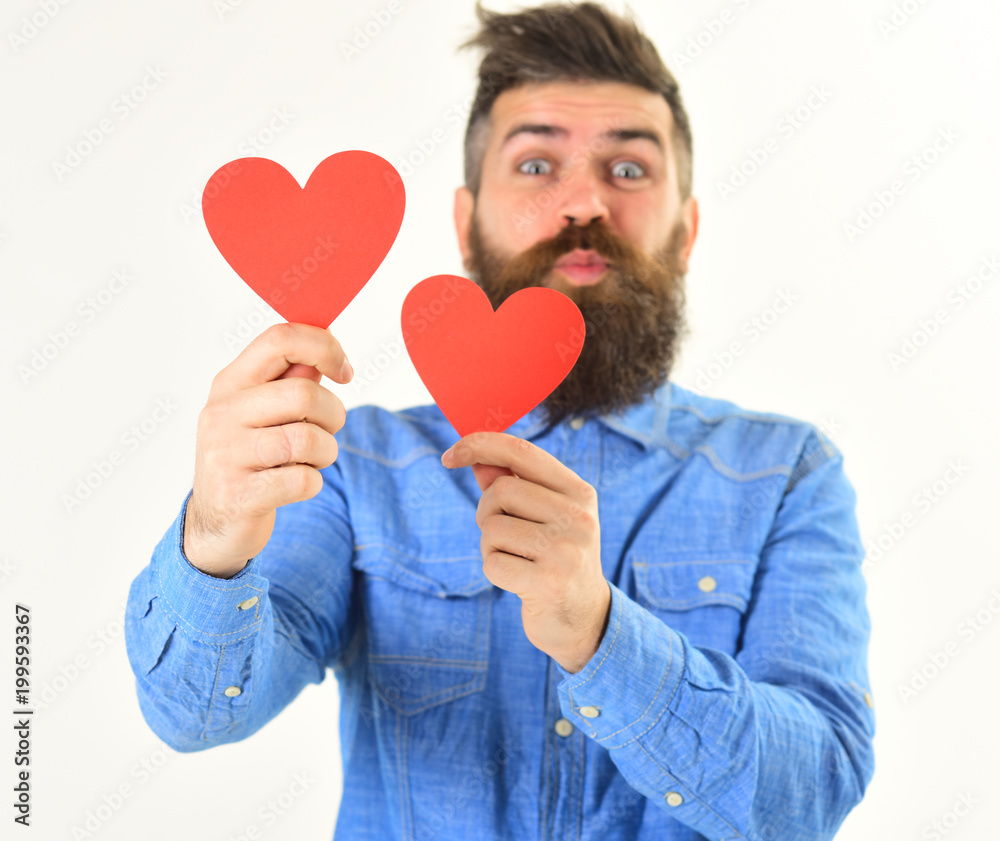 Young man with beard in denim shirt holding paper hearts Young man with beard in denim shirt holding paper hearts