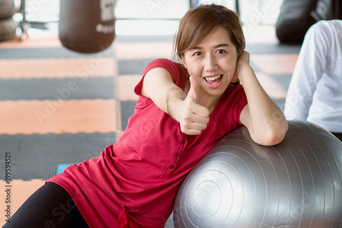 Healthy workout. Young cheerful woman showing thumbs up after enjoy workout with ball in the gym.