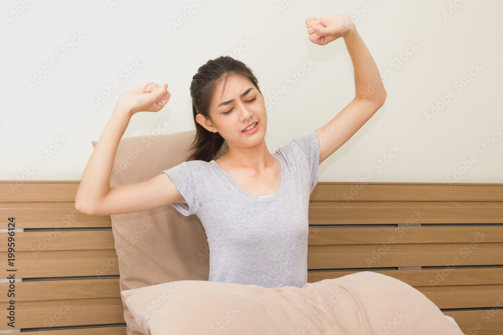 Asian young women wake up and stretching on the bed in the morning. Asian young women wake up and stretching on the bed in the morning.