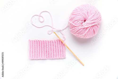 Pink ball of yarn with wooden crochet hook.