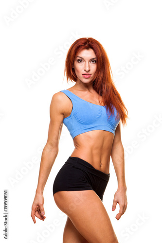 Muscular young woman athlete standing on white background. Woman bodybuilder relaxing after exercise. © satyrenko