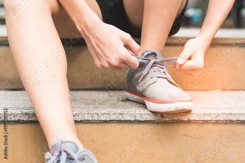 close-up hands of woman tying shoelace on the stairs prepare for jogging.