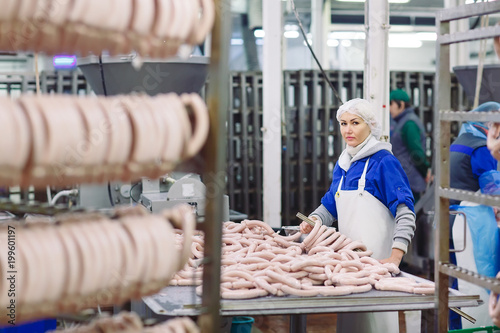 Butchers processing sausages at meat factory.